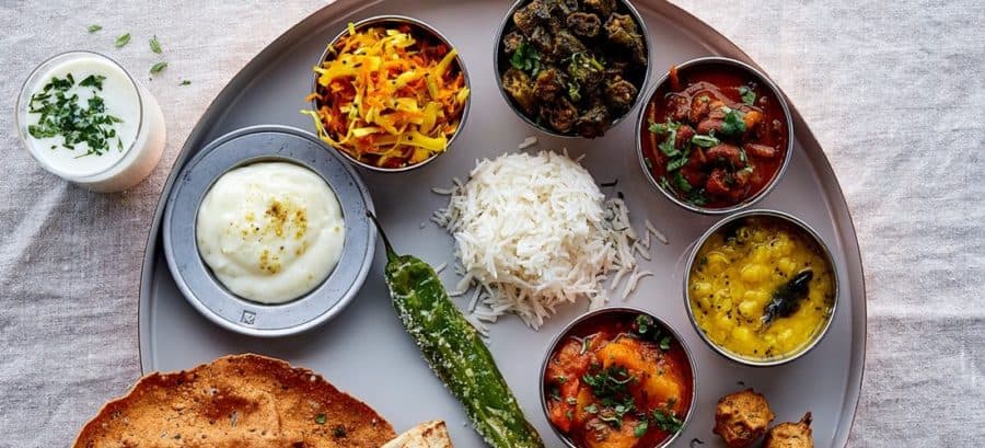 Indischer Teller mit Reis, Curry und Beilagen
